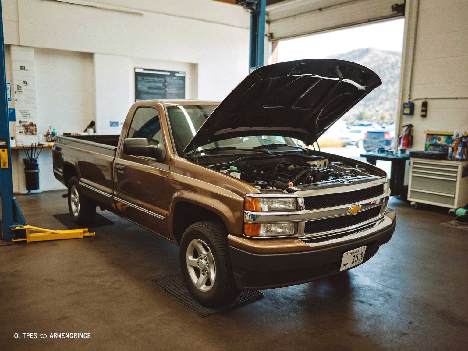 Pickup truck with its hood open in an independent repair bay, with the Colorado foothills visible outside.